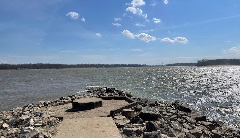 Rocky shoreline overlooking bright, windy waters.