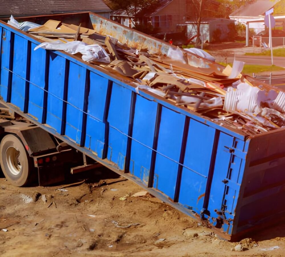 Blue construction debris container filled with rock and concrete rubble.