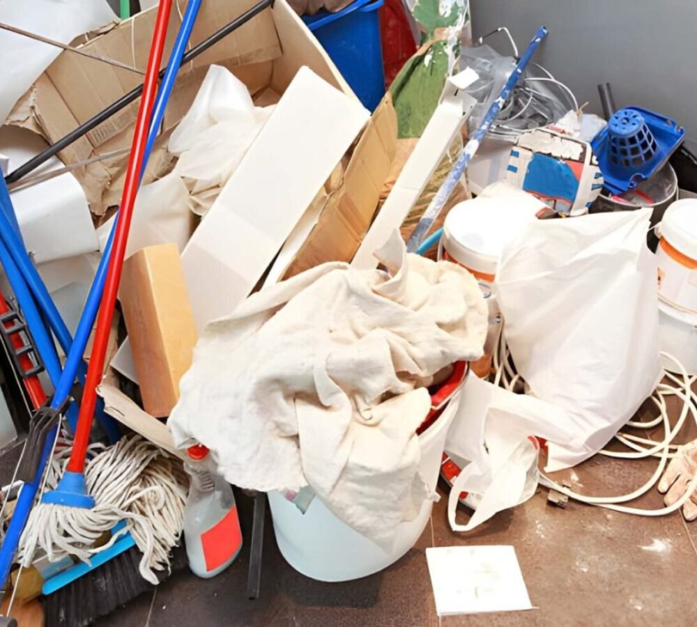 Messy pile of cleaning supplies and junk, including mops and buckets.